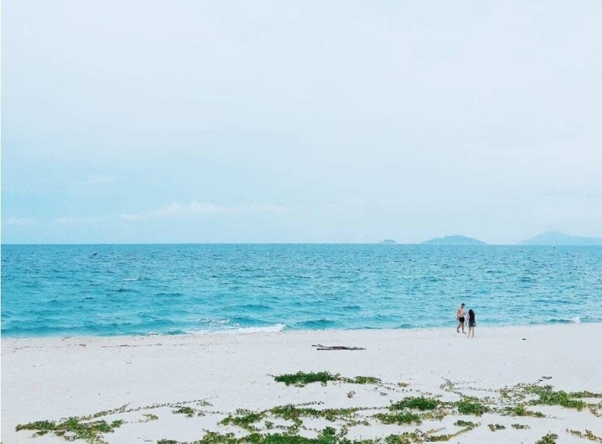 Two people on an almost empty Hà My Beach